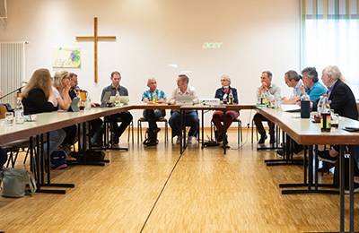 Sitzung, mehrere Personen sitzen am Tisch